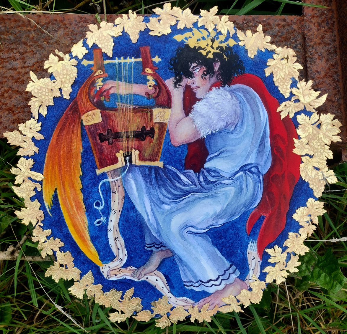 A circular painting of one figure, Orpheus. The painting is framed by gold grape leaves and clusters. Orpheus wears a blue and bright red chiton and leans over a lyre. The lyre is wooden and has ornate gold details. Orpheus looks to the left.